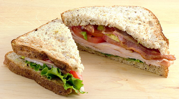 Turkey and bacon sandwich with lettuce and tomato on wheat bread.