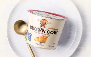Brown Cow yogurt container on white plate with spoon