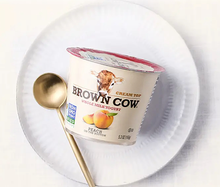 Brown Cow yogurt container on white plate with spoon